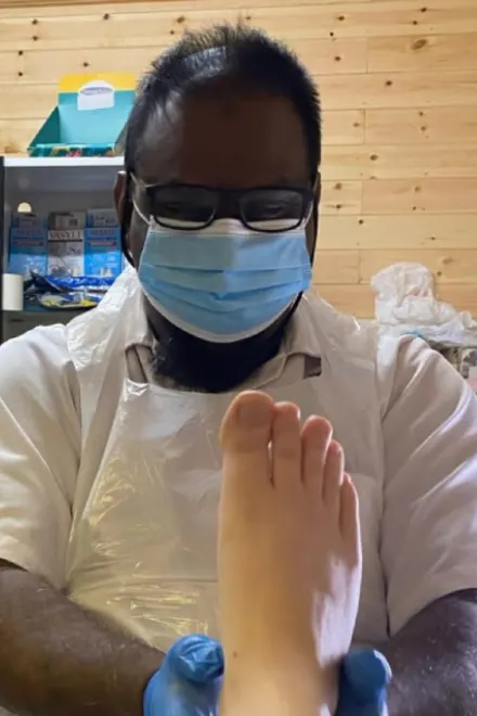 Ray in a mask and gloves treating a patient's foot