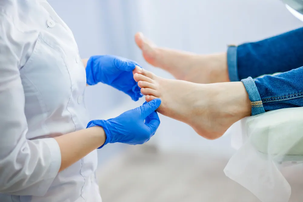 A podiatrist in blue gloves holding a patient's toes during an examination
